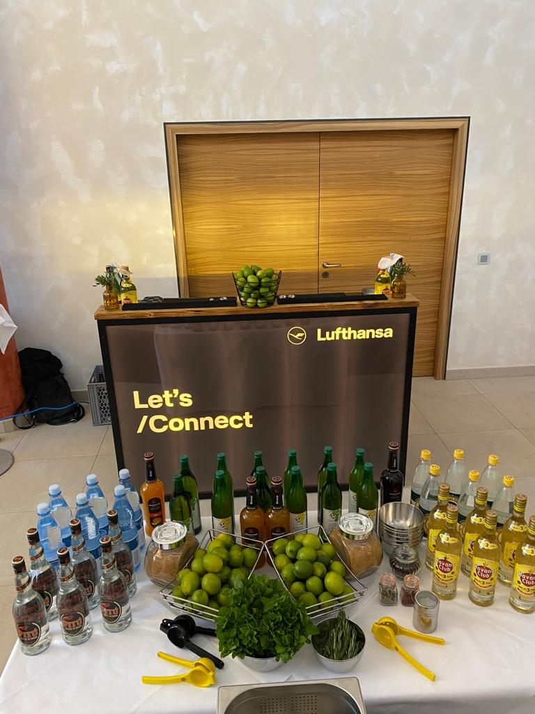 Aufgebauter Zutatentisch vor dem Kurs: Limetten und Minze in Schalen, brauner Zucker in Gläsern, gelbe Limettenpressen, dahinter Flaschen in Reihe